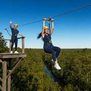 Rider zip-lining over a bayou canopy as a friend waves her off, Houston Thrilling Experience Collection experience gift