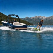 Wakeboarder carving a spray line behind a tow boat on a mountain lake, Wakeboarding & Waterskiing Lesson experience gift