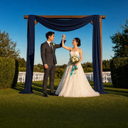 Bride and groom clasping hands beneath a garden ceremony arch, Wedding Ceremony Package experience gift