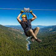Rider zipping along a cable high above a pine gorge, Zip Line Adventure experience gift